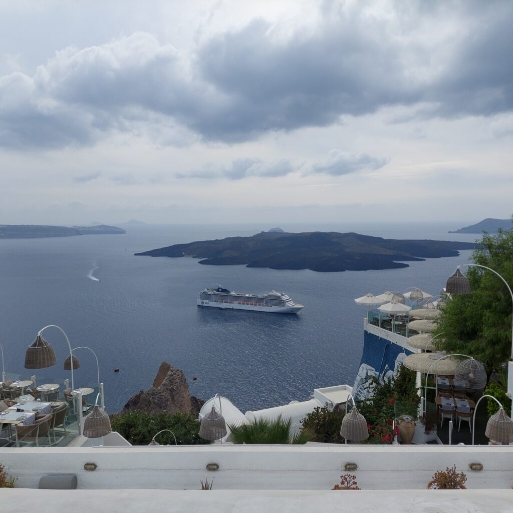 Photo taken high on a hill looking down on a large white cruise ship.